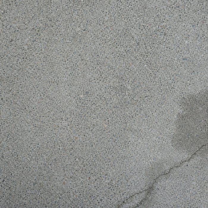 Clean grey concrete showing the aggregate, with a hairline crack and a damp patch still drying.